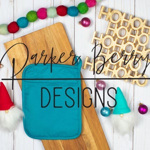 May include: A teal pot holder with the text "Parker & Berry Designs" on a wooden cutting board with a gold "Ho Ho Ho" ornament and a red and white gnome.