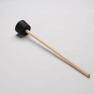 May include: A black rubber mallet with a wooden handle. The mallet is used for striking a surface to create a sound.