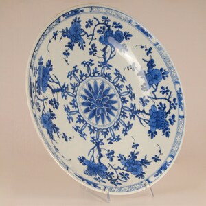 May include: A large, white porcelain bowl with a blue and white floral design. The bowl features a central medallion with a stylised flower and a border of repeating floral motifs.