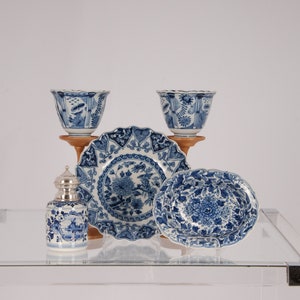 May include: A set of blue and white Delftware pottery, including a plate, two bowls, and a small jar with a silver lid. The pieces are decorated with floral patterns and intricate designs.