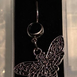 Peut inclure: Un piercing de nombril argenté avec un bijou noir et un pendentif papillon argenté.
