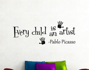 May include: Black and white wall decal with the quote "Every child is an artist - Pablo Picasso". The quote is displayed on a white wall above a black sofa with colourful throw pillows.