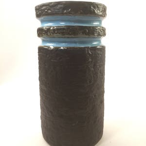 May include: A brown ceramic vase with a textured surface and two blue bands around the top.