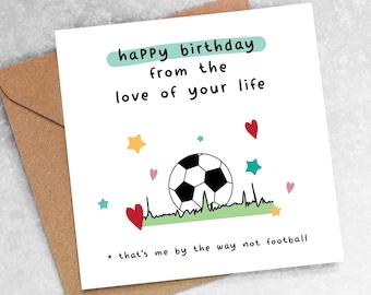 May include: A white card with a black and white illustration of a soccer ball on green grass. The card has the text "happy birthday from the love of your life" and "* that's me by the way not football".