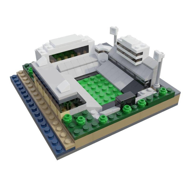 Puede incluir: Maqueta de estadio en miniatura construida con ladrillos de pl&aacute;stico entrelazados. El modelo presenta un campo verde, estructuras blancas y grises y peque&ntilde;os &aacute;rboles verdes. La base incluye elementos azules, beige y verdes, creando una representaci&oacute;n arquitect&oacute;nica detallada.