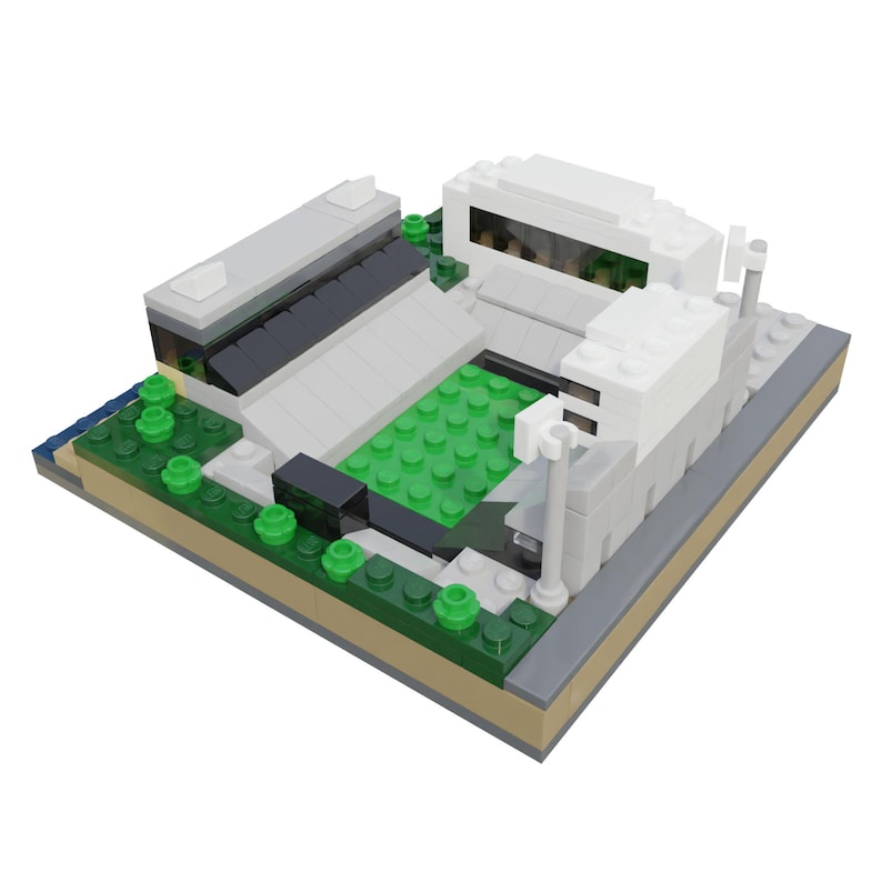 Puede incluir: Maqueta arquitect&oacute;nica en miniatura construida con bloques de juguete. El modelo presenta un edificio blanco con una gran ventana, un c&eacute;sped verde y un tejado gris. La base es una mezcla de bloques verdes, grises y beige.