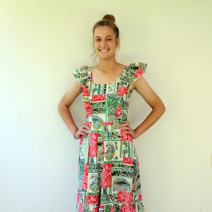 May include: A woman wearing a green, red, and white patchwork dress with a ruffled neckline and sleeves. The dress has a paisley pattern and a tiered skirt.