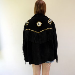 May include: Black suede jacket with gold and white embroidery and fringe detailing. The jacket has a western style.