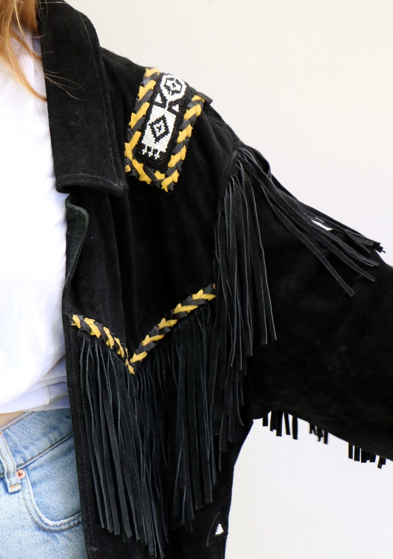May include: Black suede jacket with fringe detailing and a beaded and braided trim in yellow and white.