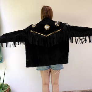 May include: Black suede jacket with gold and white embroidery and fringe detailing. The jacket has a southwestern style.