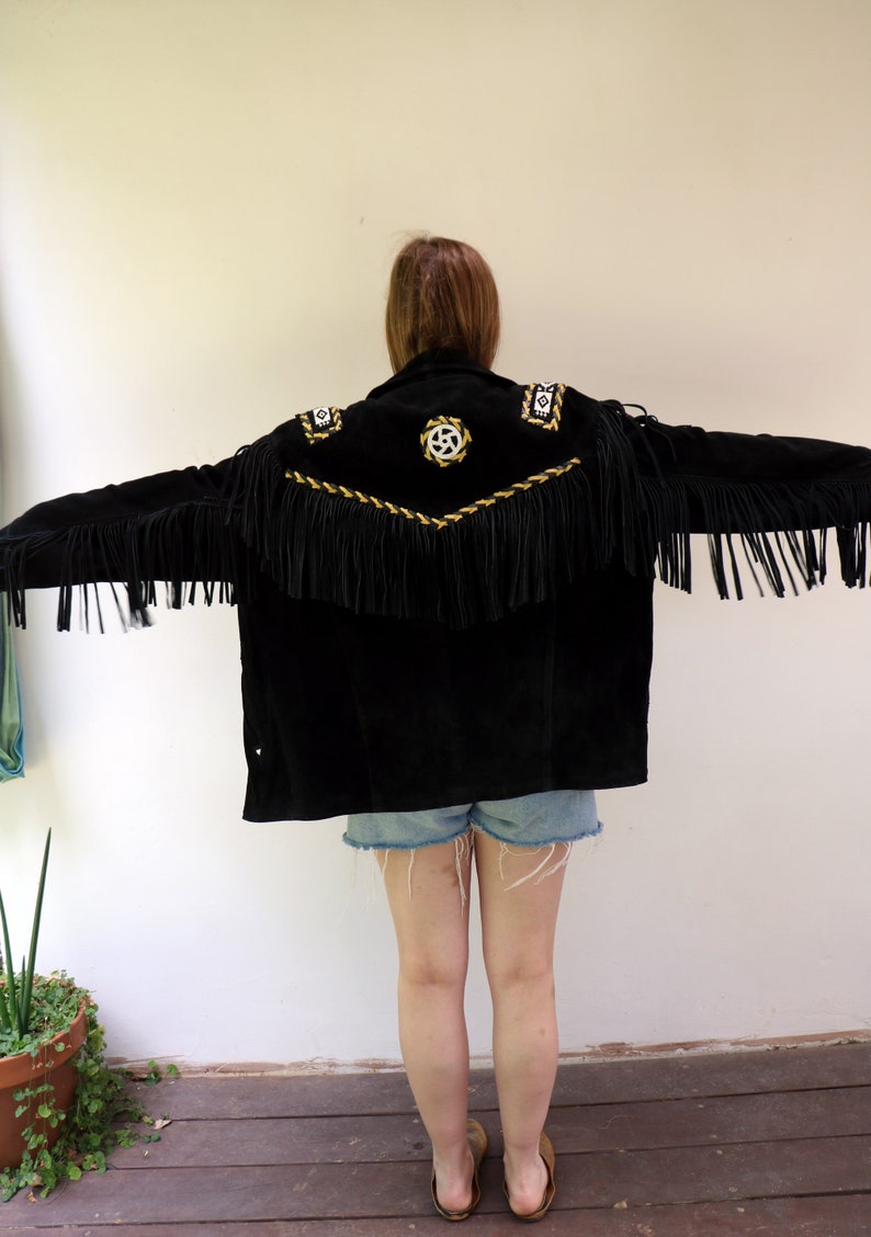 May include: Black suede jacket with gold and white embroidery and fringe detailing. The jacket has a southwestern style.