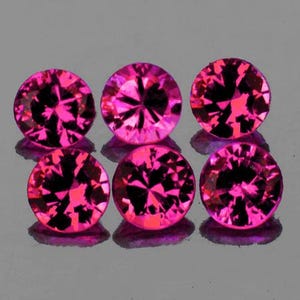 May include: Six round, faceted, pink gemstones. The gemstones are set in a row, with three on each side.