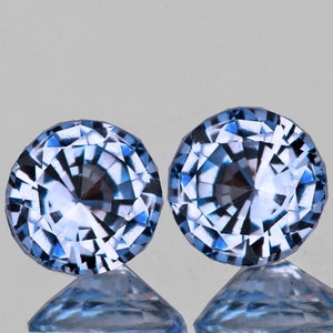 Op de afbeelding: Twee ronde, gefacetteerde, lichtblauwe edelstenen met een wit en blauw patroon.