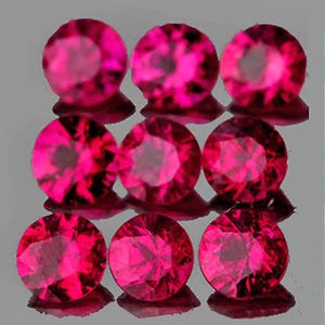 Puede incluir: Nueve gemas redondas, facetadas, de color rosa intenso están dispuestas en una cuadrícula. Las gemas tienen un corte brillante, que refleja la luz y crea un efecto brillante. Las gemas están sobre una superficie gris reflectante.