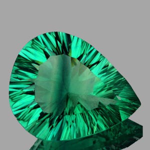 May include: A pear-shaped, faceted gemstone with a vibrant emerald green hue. The gem's intricate cuts create a play of light, enhancing its brilliance. The gemstone is set against a neutral gray background, highlighting its color and form.