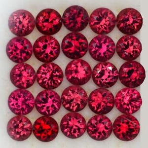 May include: Twenty-five round, faceted, red gemstones are arranged in a grid pattern. Each gem has multiple facets that reflect light, creating a sparkling effect. The gems are a deep, rich red color.