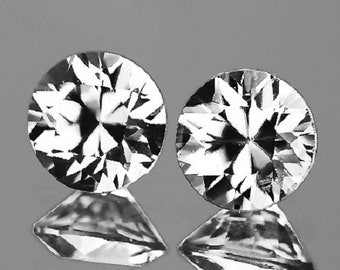 Pode incluir: Duas pedras preciosas redondas facetadas transparentes com um padrão de estrela.