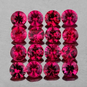 Puede incluir: Un conjunto de dieciséis piedras preciosas de corte redondo en un vibrante color rojo fucsia, dispuestas en una cuadrícula de cuatro por cuatro. Cada piedra presenta una superficie facetada que refleja la luz, creando un patrón simétrico.