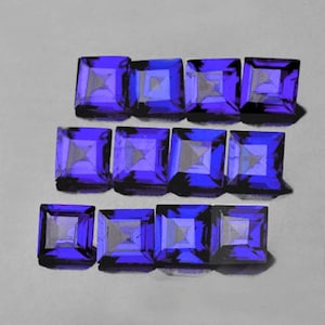 May include: A collection of ten square-shaped, faceted gemstones. The gemstones are a deep purple color with a slight blue hue.