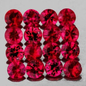 May include: A collection of sixteen round-cut, vibrant red gemstones arranged in a four-by-four grid. Each stone features a faceted surface that reflects light, creating a brilliant, deep crimson appearance with dark internal patterns.