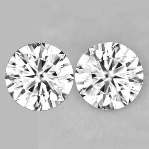 May include: Two round, brilliant-cut diamonds, each with numerous facets, are displayed against a gray background. The diamonds are white and reflect light, creating a sparkling effect. The image is a close-up, showcasing the intricate details of the gemstones.