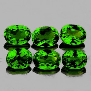 Puede incluir: Seis piedras preciosas verdes de forma ovalada, probablemente peridotos, con un corte facetado. Las piedras preciosas están dispuestas en dos filas de tres.