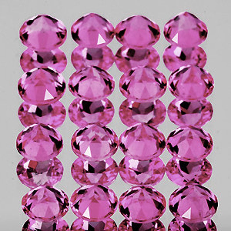 Puede incluir: Un grupo de 15 piedras preciosas ovaladas de color rosa, cada una con un corte facetado. Las piedras preciosas est&aacute;n dispuestas en tres filas de cinco, con cada fila ligeramente desplazada de la que est&aacute; arriba.