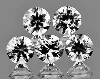 Pode incluir: Cinco pedras preciosas redondas, transparentes e facetadas. As pedras preciosas estão dispostas em forma de pirâmide, com a maior pedra no topo.