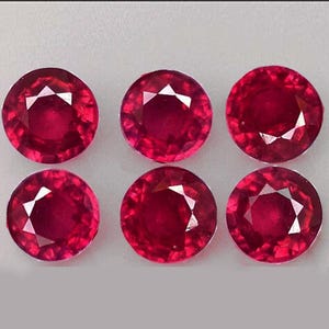 May include: Six round, red gemstones with a faceted cut. The gemstones are arranged in two rows of three.