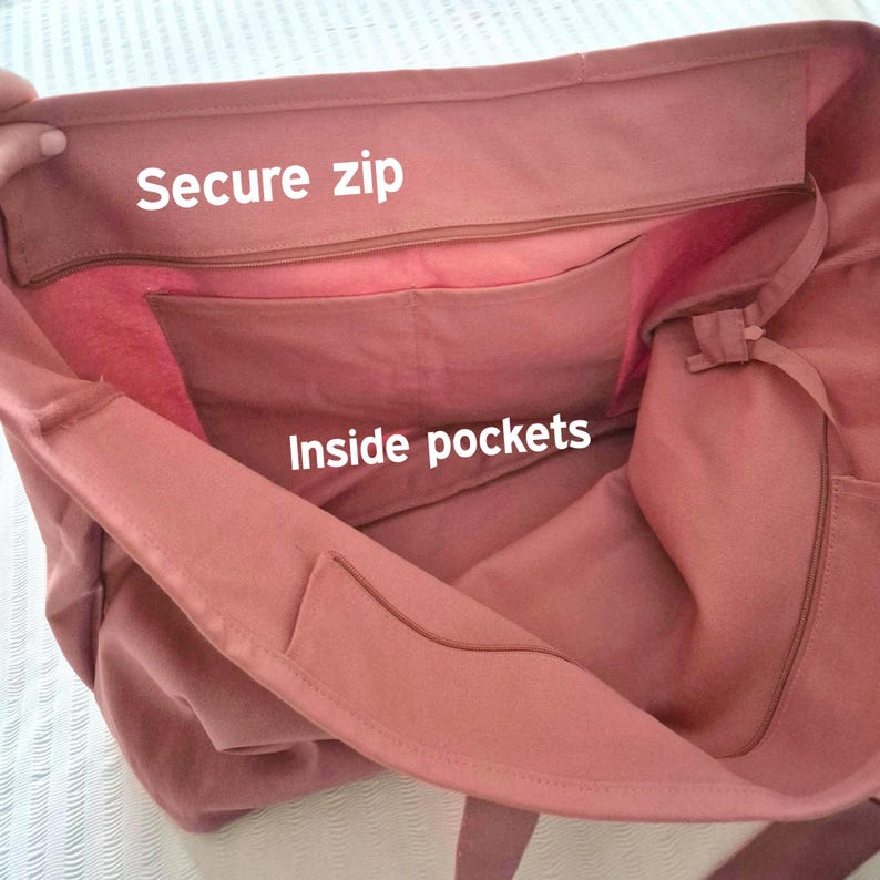 May include: A dusty rose tote bag with a secure zip closure and inside pockets. The bag is made of a soft, durable fabric. The text "Secure zip" and "Inside pockets" are visible on the bag.