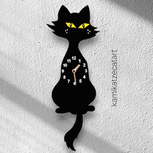 May include: Black cat-shaped wall clock with yellow eyes and a long tail. The clock face has black numbers and a gold hour and minute hand.