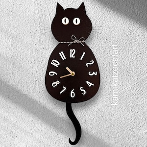 May include: Black cat-shaped wall clock with a pendulum tail and white numbers. The clock face is black with white numbers and gold hands.