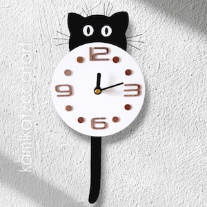 May include: A black cat-shaped wall clock with a white clock face. The clock features wooden numerals and dots, with a black tail as a pendulum. The clock is mounted on a textured white wall.