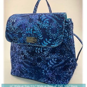 May include: A blue and white floral print convertible crossbody bag with a top flap and a zipper closure. The bag measures 12 inches wide at the top, 7 3/4 inches wide at the base, 9 inches tall, and 3 5/8 inches deep. You may sell bags you make from this pattern in small quantities, but it cannot be mass produced. This pattern may not be redistributed or reproduced in anyway.