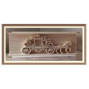 May include: A brown book with the pages folded to create a 3D sculpture of a horse-drawn carriage. The sculpture is framed in a brown frame with a white mat. The text "Folded Book Patterns by Jacqui" is printed on the mat.