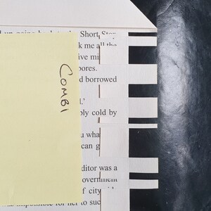 May include: A close-up of a page from a book with black and white text. The text reads "Short Story" and "k me all the pores." The text is partially obscured by a yellow sticky note with the word "COMBI" written on it.