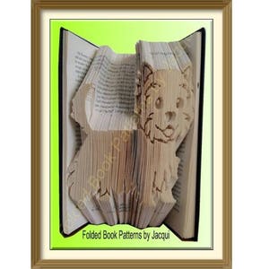 May include: A book folded into the shape of a dog, with the pages forming the dog's body and head. The dog is brown and white and has a happy expression. The book is open and the pages are visible. The text "Folded Book Patterns by Jacqui" is printed on the bottom of the image.