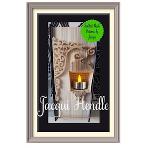 Peut inclure: Une image encadrée d'un livre plié en un motif décoratif. Le livre est plié en une forme qui ressemble à un bougeoir avec une petite bougie à l'intérieur. L'image est intitulée "Folded Book Patterns by Jacqui" et le nom de l'artiste est "Jacqui Hendle".