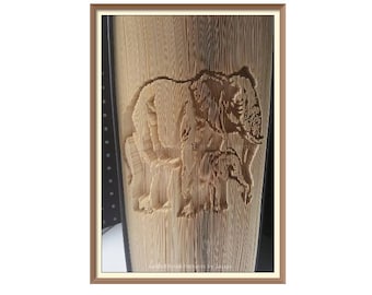 May include: A close-up of a book with a carved image of an elephant and its calf. The carving is detailed and intricate, and the book is made of a light brown material.