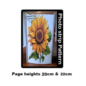 May include: A photo strip pattern book fold with a sunflower design. The book is white with a sunflower painted on the front. The pages are 20cm and 22cm high. The text "Photo strip pattern" is on the right side of the image.