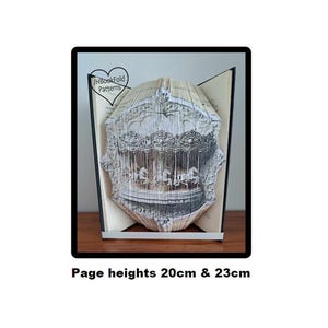 May include: A book with a 3D pop-up of a carousel, made with folded pages. The book is open and the carousel is visible. The book is 20cm and 23cm tall. The book is titled "JH Bookfold Patterns".