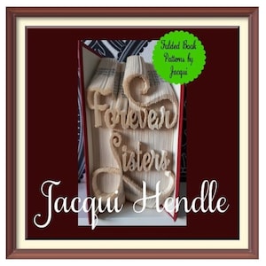 Può includere: Un'opera d'arte di libro incorniciata con le parole "Forever Sisters" piegate nelle pagine. Il libro è aperto e le pagine sono piegate in un design 3D. Il nome dell'artista, "Jacqui Hendle", è scritto sotto l'opera d'arte del libro. Un cerchio verde con il testo "Folded Book Patterns by Jacqui" è nell'angolo in alto a destra dell'immagine.