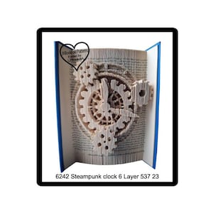 May include: A unique paper art piece featuring a steampunk clock design. The clock is intricately cut from the pages of a book, showcasing gears and clock hands. The book's pages are visible, with blue covers. Text at the bottom reads "6242 Steampunk clock 6 Layer 537 23".