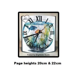 May include: A white clock face with Roman numerals and black hands. The clock face is surrounded by a blue and green watercolor design of fish and seaweed. The clock is 20 cm or 22 cm tall. "Folded by Brightside Studio" is printed below the clock.
