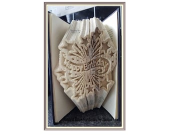 May include: A book folded into a 3D design that says "Happy Birthday" with stars around it. The book is open and the design is visible from the front.