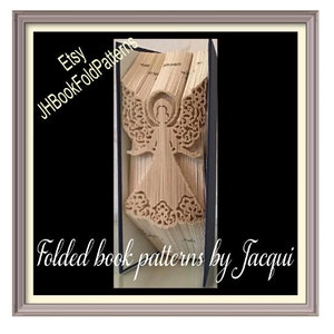 May include: A folded book art piece in the shape of an angel. The book is made of old, worn pages and is framed in a silver frame. The text on the frame reads "Etsy JHBookFoldPatterns Folded book patterns by Jacqui".