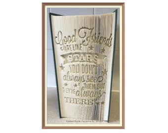 May include: A folded book art piece with the quote "Good Friends are like Stars, You don't always see them but they're always there" carved into the pages. The book has a green spine and a brown frame.