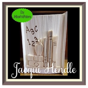 Könnte beinhalten: Ein weißes Buch, das zu einem Bücherregal gefaltet ist, mit einem Apfel, Bleistiften und Büchern. Das Buch hat die Buchstaben "ABC" und die Zahlen "123" eingegraben. Der Text "Etsy JHBookFoldPatterns" und "Jacqui Hendle" ist auf dem Bild zu sehen.