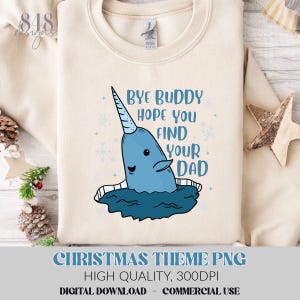Op de afbeelding: Een crèmekleurige sweatshirt met een blauwe narwalafbeelding en de tekst "Bye Buddy Hope You Find Your Dad". De narwal heeft een lange, spiraalvormige hoorn en is omringd door sneeuwvlokken. De onderkant van de sweatshirt heeft de tekst "CHRISTMAS THEME PNG".