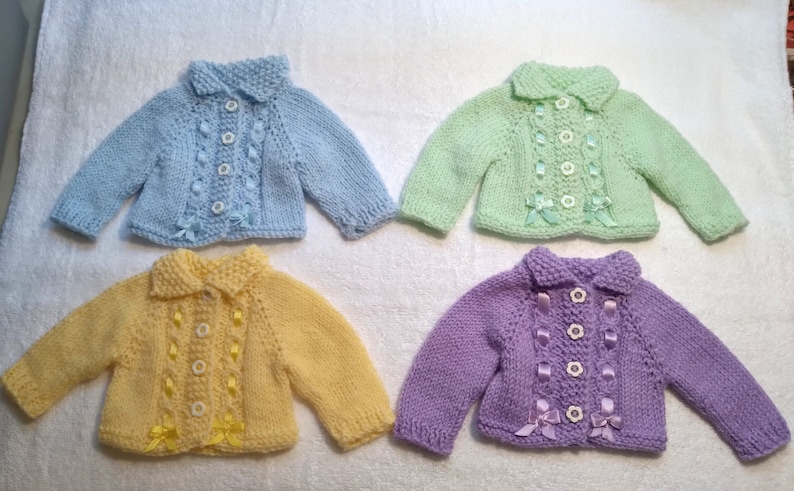 Puede incluir: Cuatro c&aacute;rdigans de punto para beb&eacute; en diferentes colores pastel: azul claro, verde claro, amarillo y morado. Cada c&aacute;rdigan tiene un cierre de bot&oacute;n blanco, un cuello y un detalle de cinta.